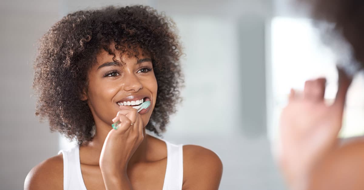 African American woman brushing teeth.