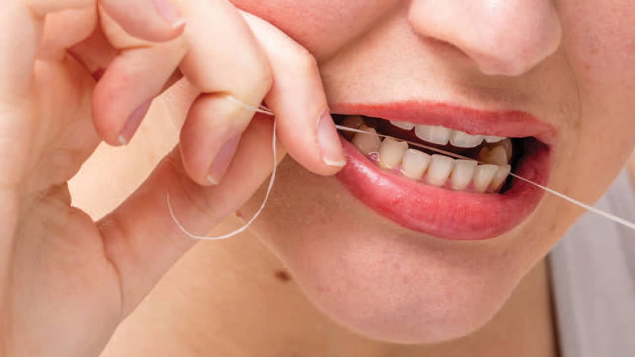 Woman practicing self-care by using dental floss