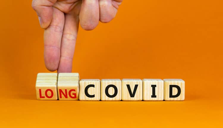 Long covid symbol. Doctor turnes wooden cubes and changes words 'covid' to 'long covid'.