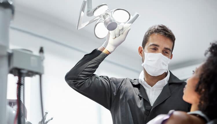 Dentist adjusting surgical light in dental clinic