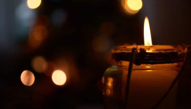 Candle flame in the evening with warm lights in the background
