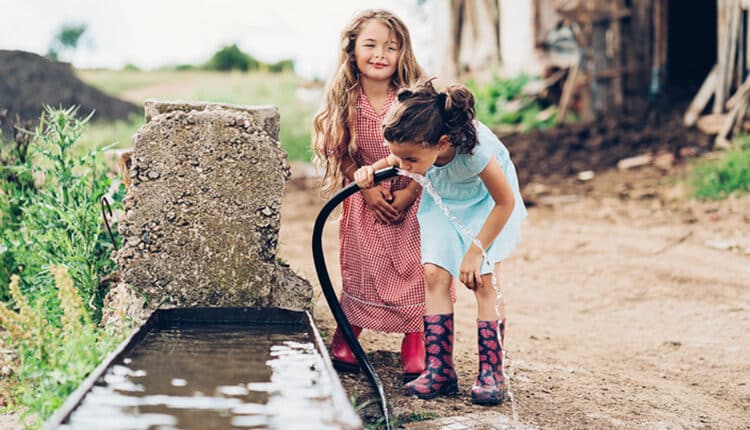 Little girls drinking water from a hose