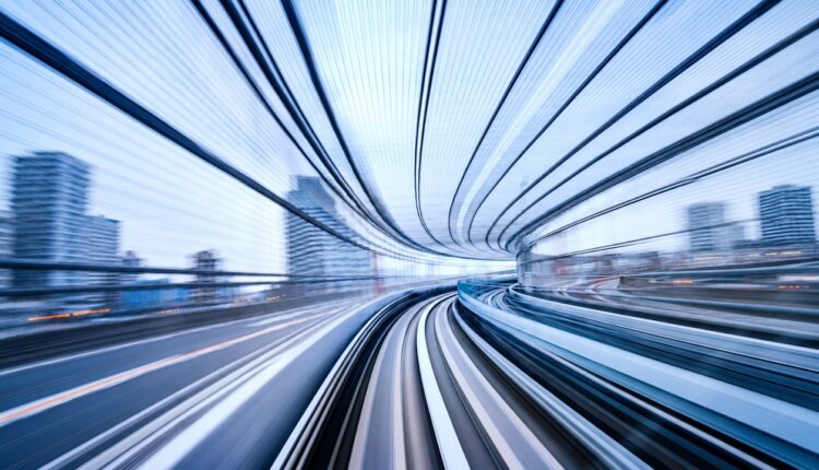Motion-blurred view along a curving monorail track through Tokyo