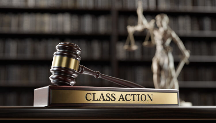 Judge’s gavel above a Class Action plaque with a justice statue in the background